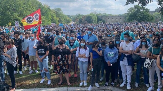 Des milliers d'étudiants masqués rassemblés avec pancartes et drapeaux.
