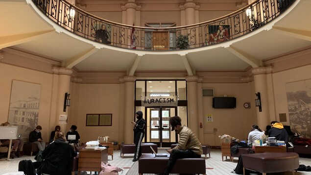 Des étudiants dans le hall d'un établissement font un sit in.