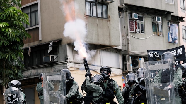 Des policiers avec des boucliers tirent des gaz lacrymogène en l'air