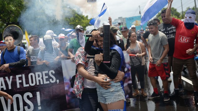 Une foule de manifestants entourent un homme et une jeune femme dont celle-ci tient dans ses mains un mortier fait maison Une foule de manifestants entourent un homme et une jeune femme dont celle-ci tient dans ses mains un mortier fait maison