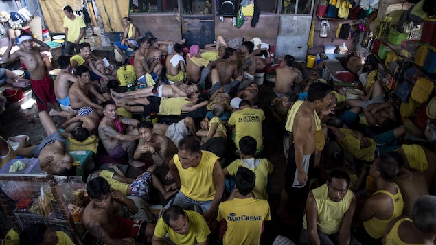 Des dizaines d'hommes revêtus de maillots jaunes s'entassent dans une grande pièce. Des dizaines d'hommes revêtus de maillots jaunes s'entassent dans une grande pièce.