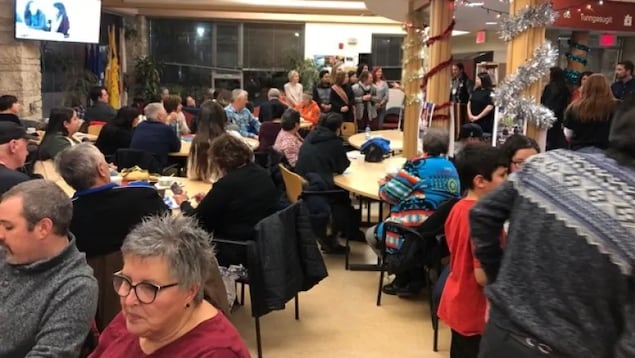 Un groupe de personnes dans une salle décorée autour de plusieurs tables.