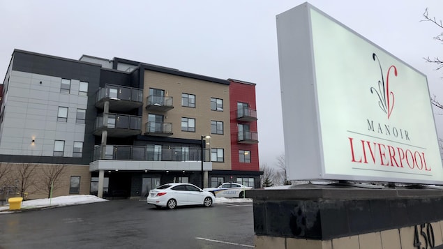 Affiche de couleur blanche devant un immeuble.