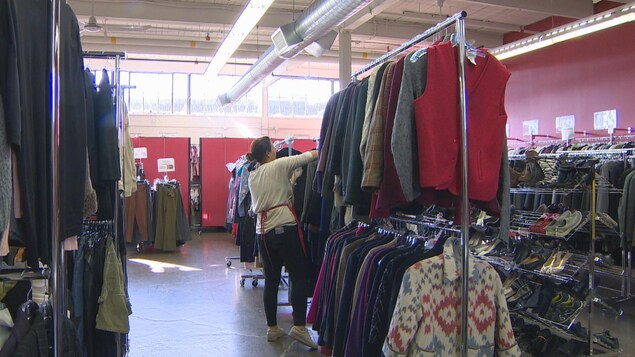 Des rayons de vêtements et de chaussures avec une personne au centre qui cherche dans un rayon. Des rayons de vêtements et de chaussures avec une personne au centre qui cherche dans un rayon.