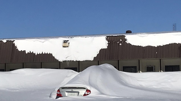 Une voiture est complètement disparue sous la neige poussée par le vent.
