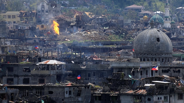 Des flammes s’élèvent dans des édifices de Marawi, aux Philippines, le 23 octobre 2017, après que des troupes gouvernementales philippines ont libéré la ville de combattants membres du groupe armé État islamique. Des flammes s’élèvent dans des édifices de Marawi, aux Philippines, le 23 octobre 2017, après que des troupes gouvernementales philippines ont libéré la ville de combattants membres du groupe armé État islamique.