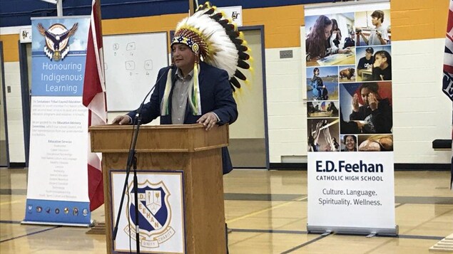 Marc Arcand, le chef du Conseil tribal de Saskatoon portant une coiffe autochtone s'exprime à la tribune