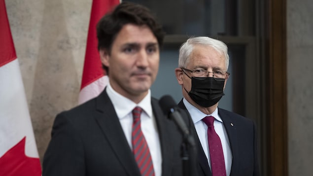 Foreign Minister Marc Garneau stands behind Prime Minister Justin Trudeau.