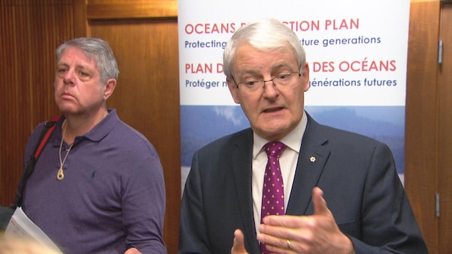 Le ministre fédéral des transports, Marc Garneau, s'adresse aux médias de Vancouver devant une affiche sur le plan de protection des océans. Le ministre fédéral des transports, Marc Garneau, s'adresse aux médias de Vancouver devant une affiche sur le plan de protection des océans.