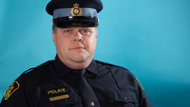 Un policier en uniforme posant pour une photo officielle.