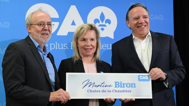 Marc Picard, Martine Biron et François Legault posent ensemble devant un log de la CAQ.