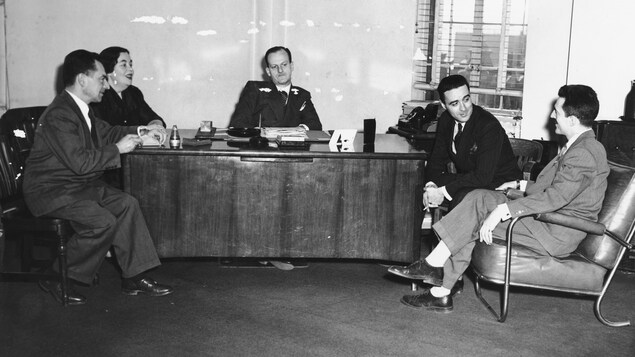 En discussion assis dans un bureau, Marcel Henry, Marcelle Barthe, Marcel Ouimet, Guy Mauffette et René Lecavalier. En discussion assis dans un bureau, Marcel Henry, Marcelle Barthe, Marcel Ouimet, Guy Mauffette et René Lecavalier.