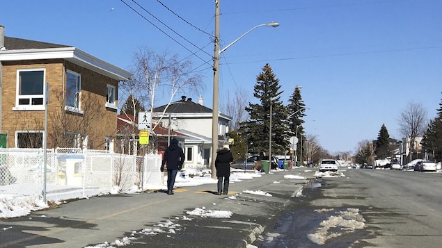 Deux personnes marchent sur le trottoir.