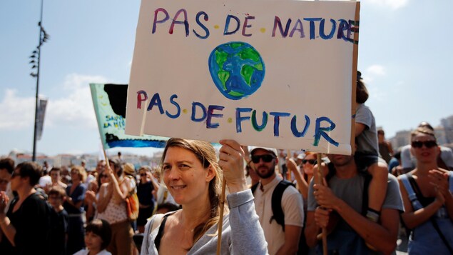 Une femme tient une pancarte sur laquelle on peut lire « Pas de nature, pas de futur ». Une femme tient une pancarte sur laquelle on peut lire « Pas de nature, pas de futur ».