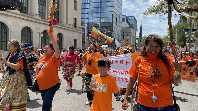 أشخاص يرتدون ألواناً برتقالية يشاركون في مسيرة تضامنية مع السكان الأصليين في أوتاوا في يوم كندا الوطني.