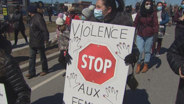 Une femme tient un pancarte qui dénonce la violence faite envers le femmes.