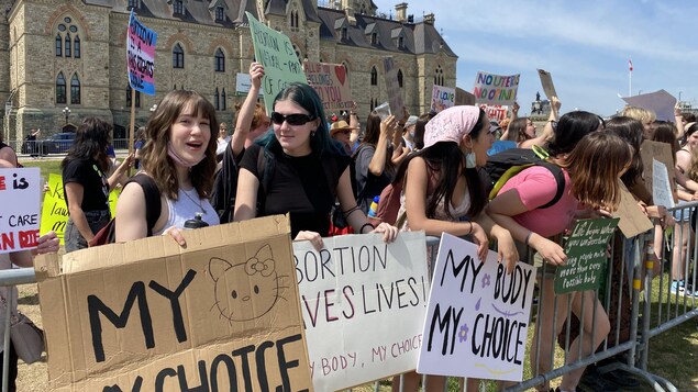 Des contre-manifestants à la Marche pour la vie, sur la colline du Parlement, à Ottawa, brandissent leurs pancartes.