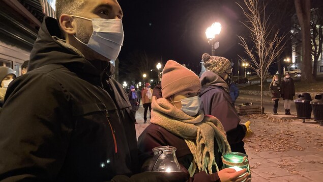 Des gens tiennent des lanternes dans leurs mains. Ils sont masqués.