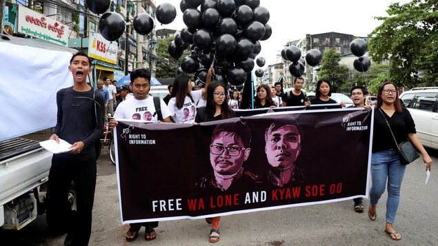 Des gens marchent avec une banderole sur laquelle ils demandent la libération des journalistes Wa Lone et Kyaw Soe Oo, de Reuters.