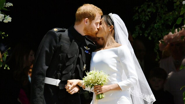 Le couple s'embrasse; la mariée tient un bouquet. Le couple s'embrasse; la mariée tient un bouquet.
