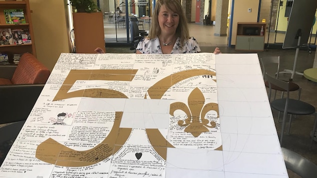 La coordonnatrice du programme d'immersion en français Marie-Eve Bussières présente une affiche du 50e anniversaire de la Cité décorée par les étudiants. La coordonnatrice du programme d'immersion en français Marie-Eve Bussières présente une affiche du 50e anniversaire de la Cité décorée par les étudiants.