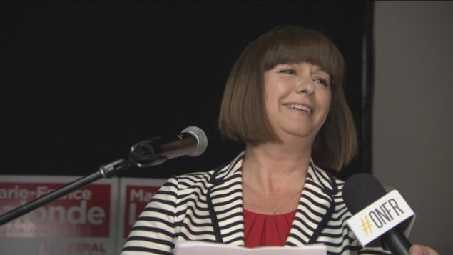 Marie-France Lalonde est debout devant un micro dans une salle.