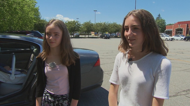 Deux soeurs debout devant une voiture dans un stationnement à Montréal Deux soeurs debout devant une voiture dans un stationnement à Montréal