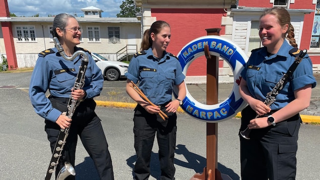 Les trois musicennes sont dehors, devant un édifice de la base navale d'Esquimalt, le 23 juin 2022.