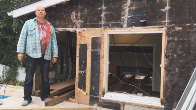 Un homme se tient à côté d'une maison au plafond particulièrement bas. Un homme se tient à côté d'une maison au plafond particulièrement bas.
