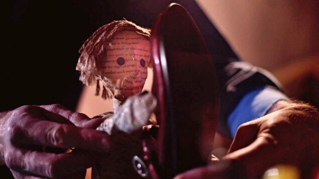 Une marionnette d'un jeune homme en papier mâché qui s'approche d'un soulier.