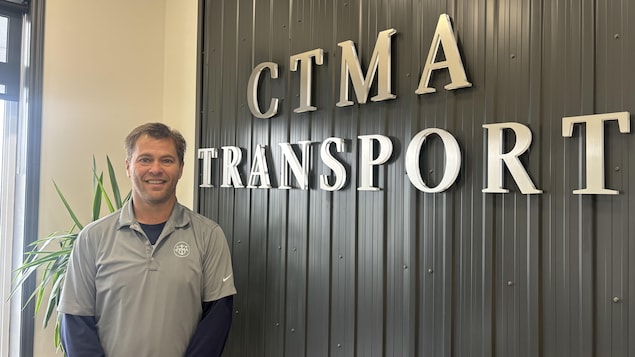 Marius Arseneaut devant un mur sur lequel est inscrit CTMA Transport. 