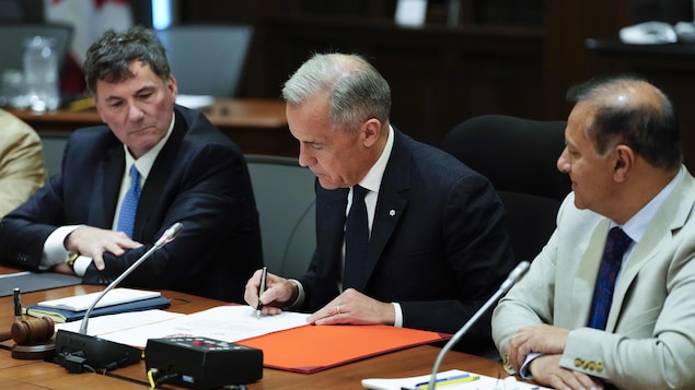 M. Carney signe un document.