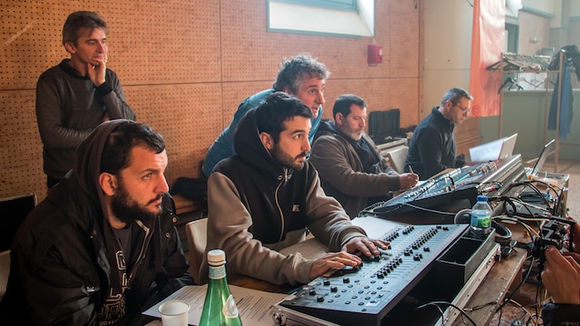 Martin Ferron aux côtés des techniciens, devant des consoles