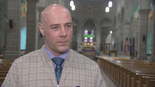 Le président de la Société nationale de l’Acadie, Martin Théberge, parle à la caméra. Il est dans une cathédrale. 