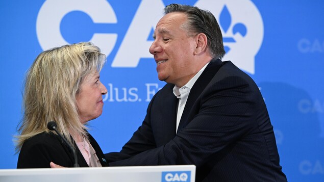 Martine Biron et François Legault devant une bannière de la CAQ.