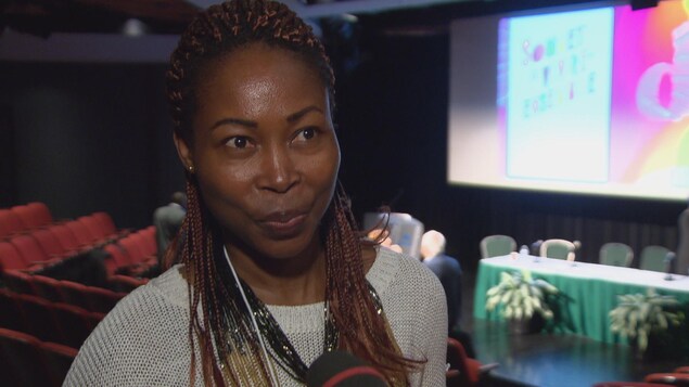 Une femme en entrevue à la caméra de Radio-Canada dans un auditorium. Une femme en entrevue à la caméra de Radio-Canada dans un auditorium.