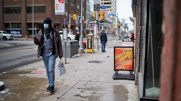 Un homme marche en portant un masque au centre-ville d'Ottawa.