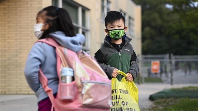 Deux élèves portent le masque à l'extérieur d'une école à Toronto.