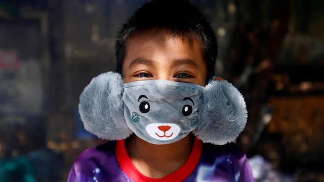 Un jeune garçon, les yeux rieurs, porte un masque qui a l'apparence d'un ours en peluche.