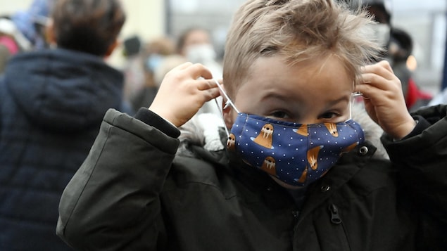 Un enfant installe son masque sur son visage espiègle.