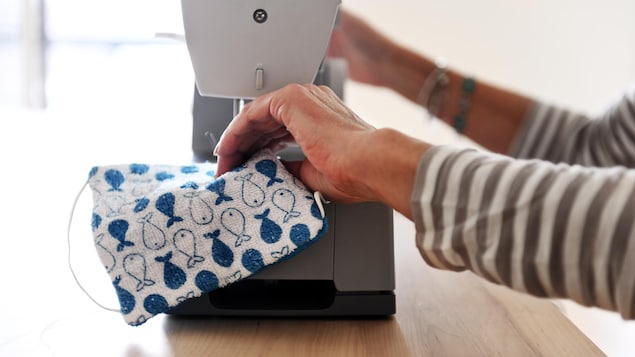 Une dame conçoit un masque artisanal à l'aide d'une machine à coudre.