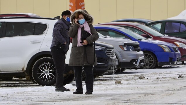 Deux personnes circulent dans un stationnement et portent un masque.