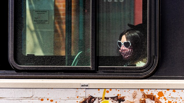 Une femme portant un masque est assise dans un autobus à Montréal.