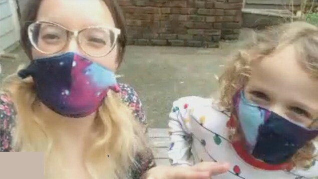 Une mère et sa fille portent des masques chirurgicaux en tissus, faits ''maison''.