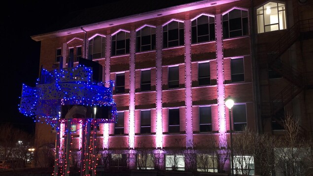 Un bâtiment éclairé par des lumières de couleurs au centre-ville de Matane en pleine nuit.