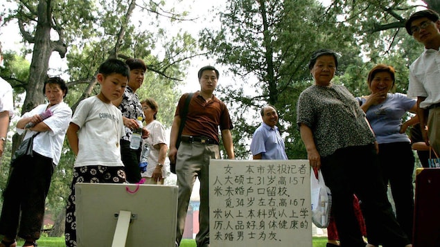 Parents look at signs detailing information about the adult children of other parents at an informal matchmaking meeting in Zhongshan Park in Beijing Thursday, July 14, 2005. Hundreds of mothers and fathers gather in the park twice a week in a determined do-it-yourself hunt for a life partner worthy of their offspring. While China now has more than 20,000 registered matchmaking agencies, some parents prefer to take matters into their own hands in finding partners for their children.  (AP Photo/