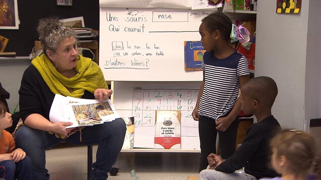Une enseignante lit un livre à plusieurs enfants attentifs. Une enseignante lit un livre à plusieurs enfants attentifs.