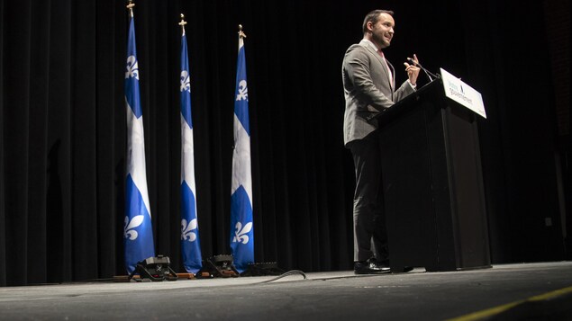 Le ministre de la Famille, Mathieu Lacombe, debout durant une conférence de presse.