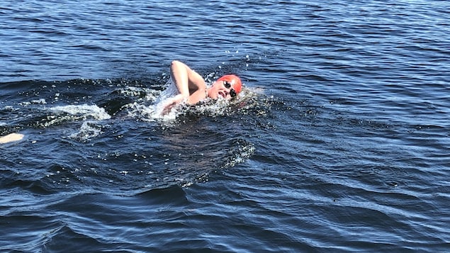 Mathis Bourbonnais nage dans l'eau. Sa tête est hors de l'eau puisqu'il prend une respiration.