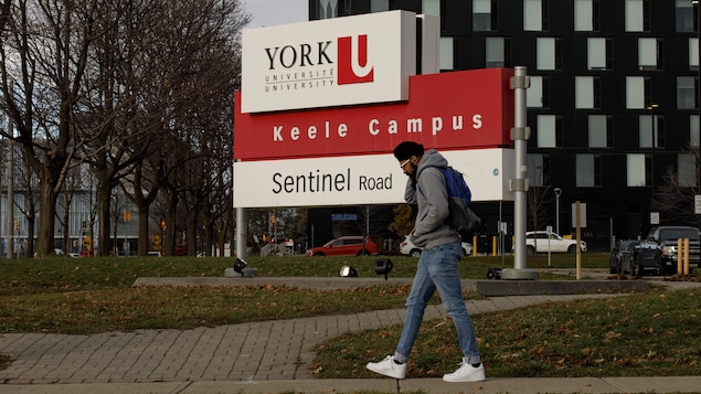 Un étudiant marche devant le panneau de l'Université York.
